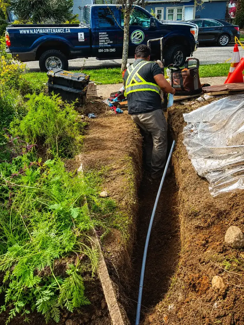Drainage worker installing pipe in residential trench in Vancouver